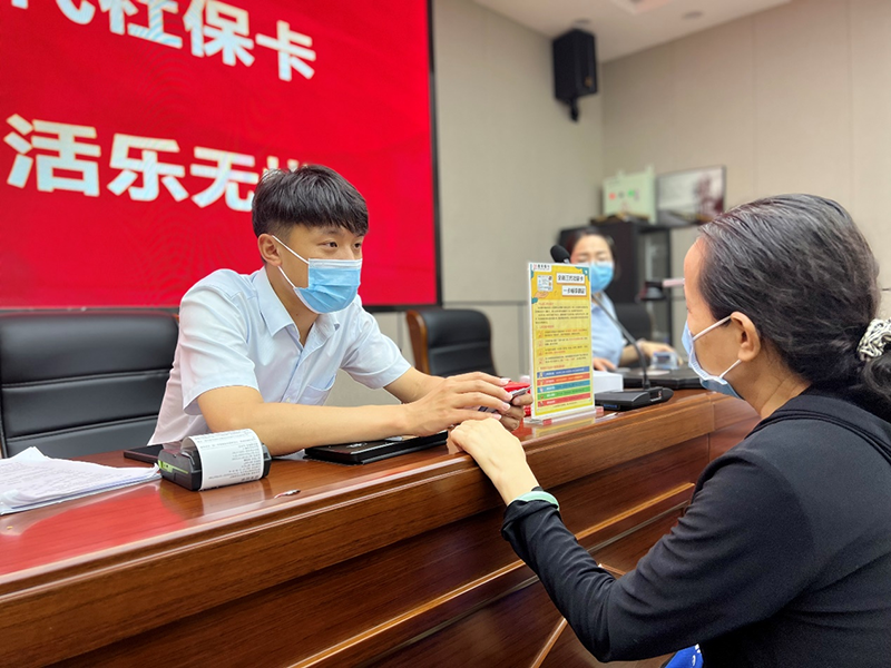 (圖為工作人員正在給社區(qū)居民現(xiàn)場更換社??ā趵驍z)
