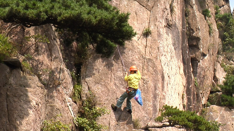李培生在懸崖上撿拾垃圾。 余建輝 攝