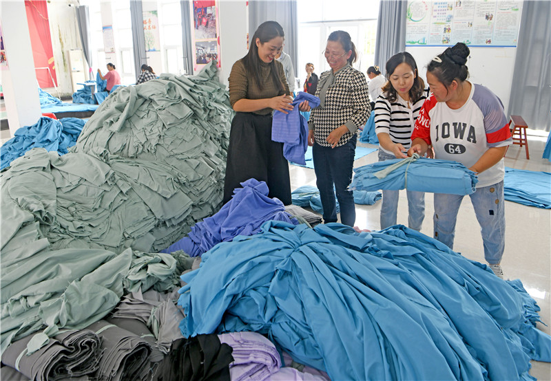 村“兩委”帶著群眾學(xué)習(xí)加工被套等家居用品出口海外。陳彬攝