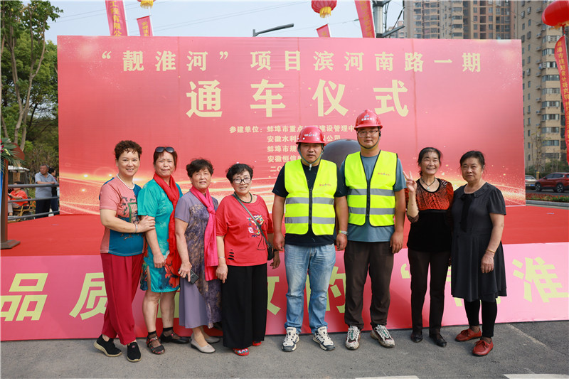 市民在通車現(xiàn)場與工程建設(shè)者合影。