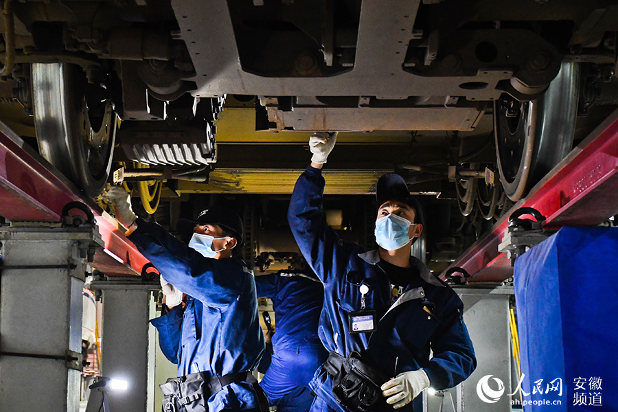 動車“醫(yī)生”們在車底檢查動車零部件。人民網 周坤攝