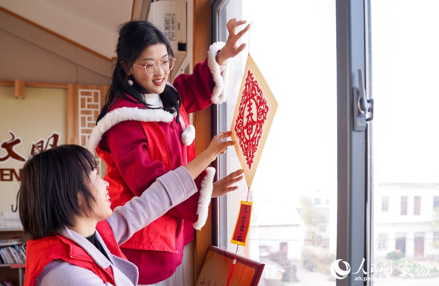 志愿者和留守兒童剪紙迎新春。人民網(wǎng) 王銳攝
