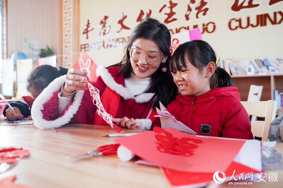 志愿者和留守兒童剪紙迎新春。人民網(wǎng) 王銳攝