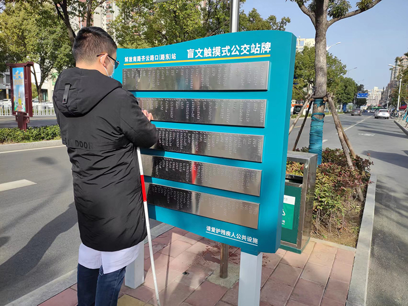 王湑正在觸摸盲文公交站牌。六安市交通運(yùn)輸局供圖