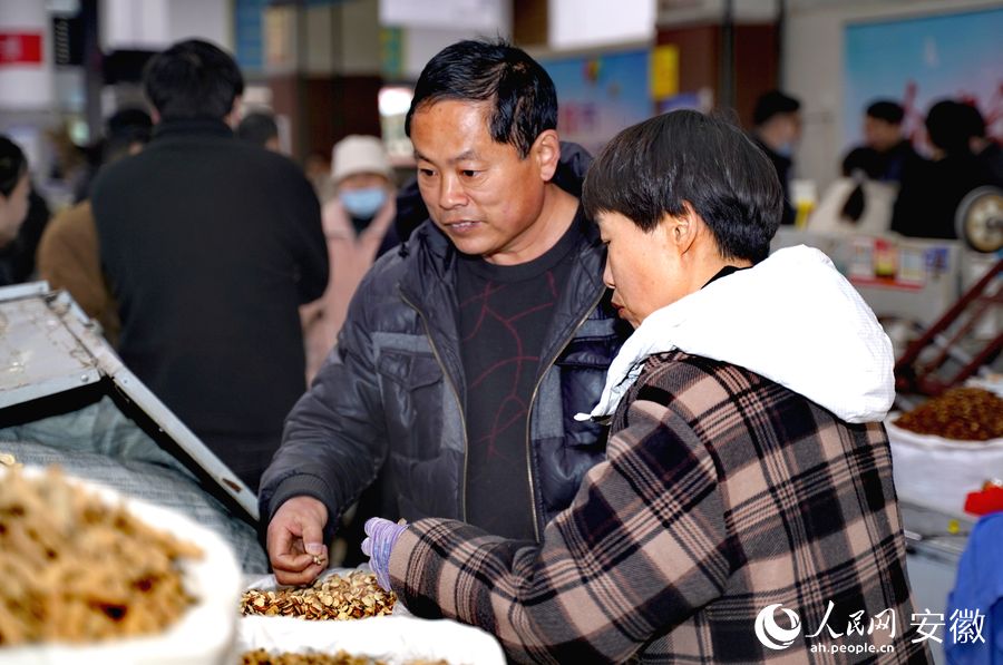 顧客正在中藥材市場里的攤位前挑選中藥材。人民網(wǎng) 王銳攝