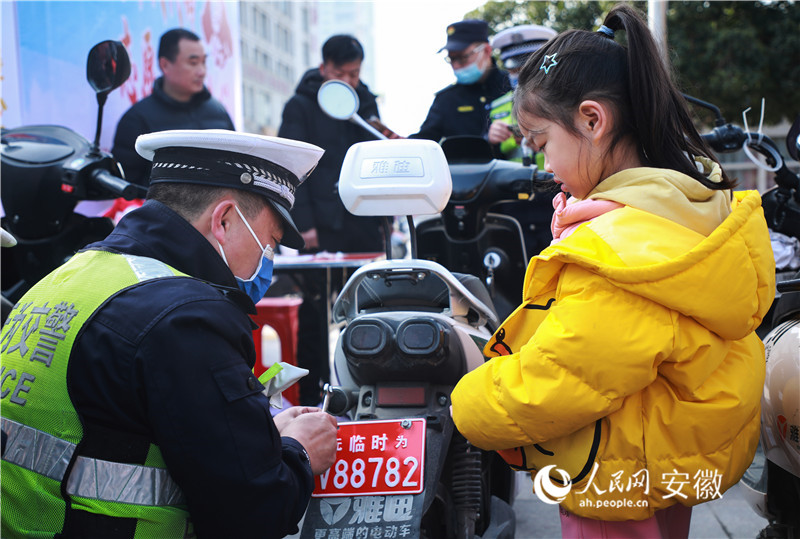 c無(wú)為市公安局交管大隊(duì)志愿服務(wù)隊(duì)正在給當(dāng)?shù)鼐用竦碾妱?dòng)自行車免費(fèi)上牌。人民網(wǎng) 陶濤攝