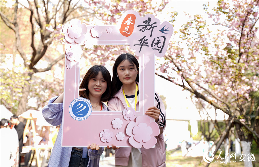 學生舉著活動的牌子拍照留念。人民網(wǎng) 王銳攝