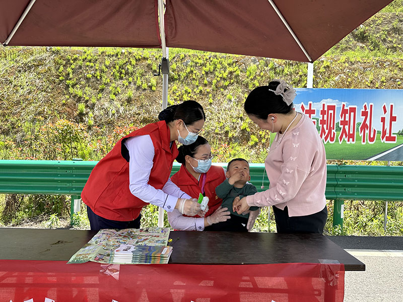 東黃山站志愿者在道口幫助獨(dú)自駕車的寶媽照顧寶寶。皖通高速供圖