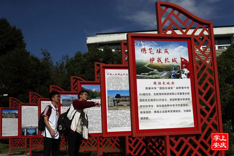 野寨中學(xué)校園內(nèi)“軍味”濃厚，廣場上兩名新生認(rèn)真觀看“攜筆從戎、護(hù)我長城”宣傳牌。儲永志攝