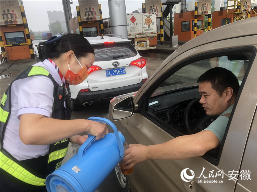 高速收費(fèi)站工作人員正在為過(guò)往司機(jī)倒水。人民網(wǎng)記者 王銳攝