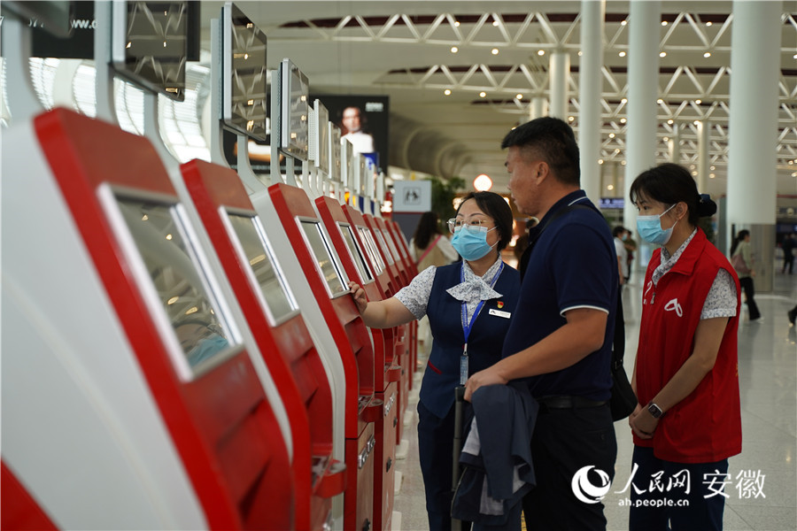 合肥新橋國際機場內工作人員正在指導旅客購票取票。人民網記者 王銳攝