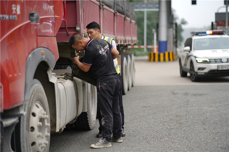 1六安北中心古碑收費(fèi)站收費(fèi)員畢偉幫助貨車師傅一起給車輛加油。