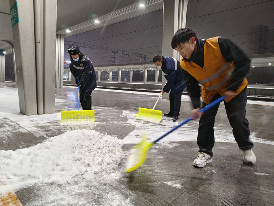 工作人員深夜清掃站臺積雪，為雪夜旅客出行鋪設(shè)安全通道。宿州火車站供圖