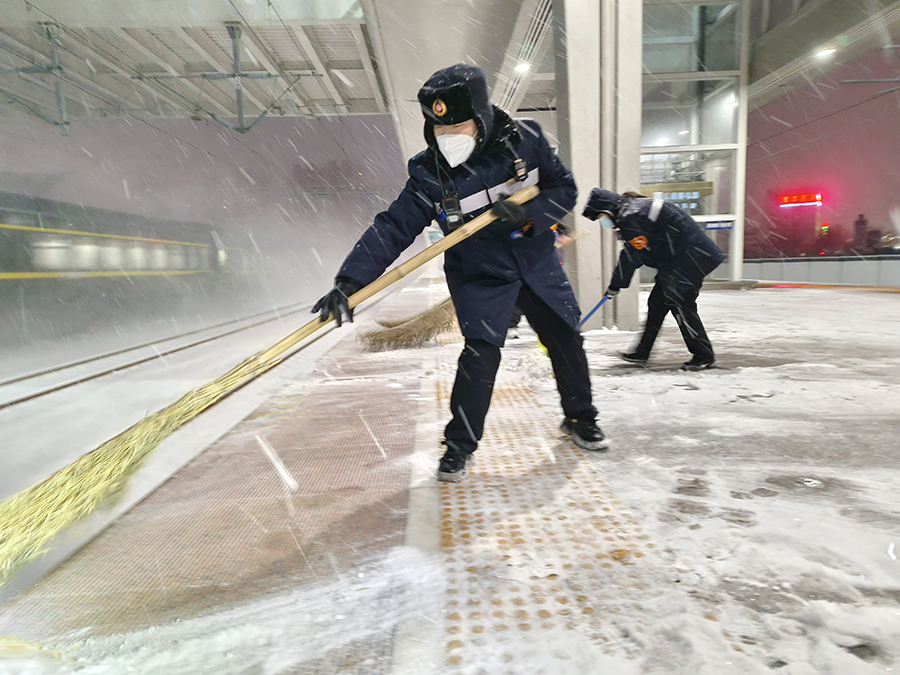 工作人員深夜清掃站臺積雪，為雪夜旅客出行鋪設(shè)安全通道。宿州火車站供圖