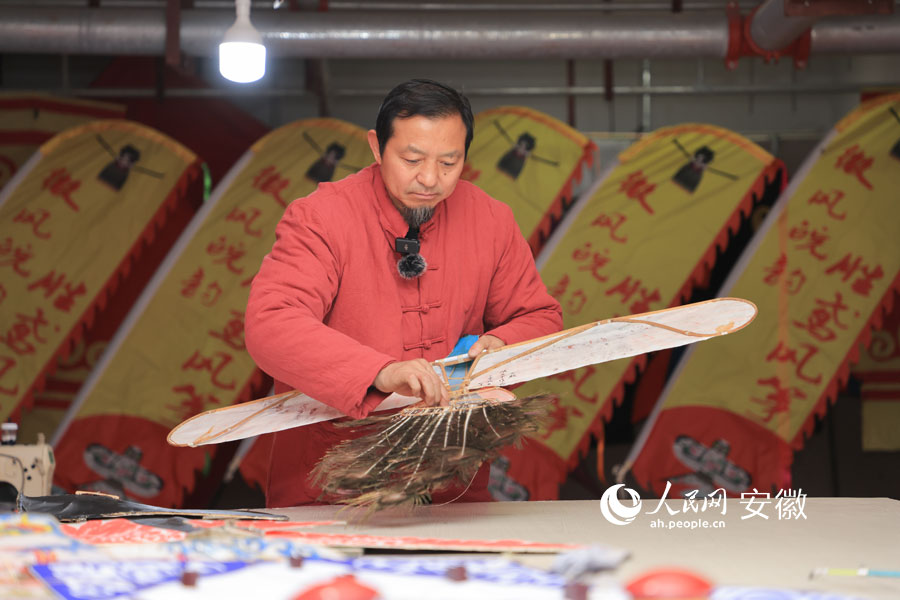 余又勝給一只鳥型風(fēng)箏裝上孔雀羽。人民網(wǎng)記者 王曉飛攝
