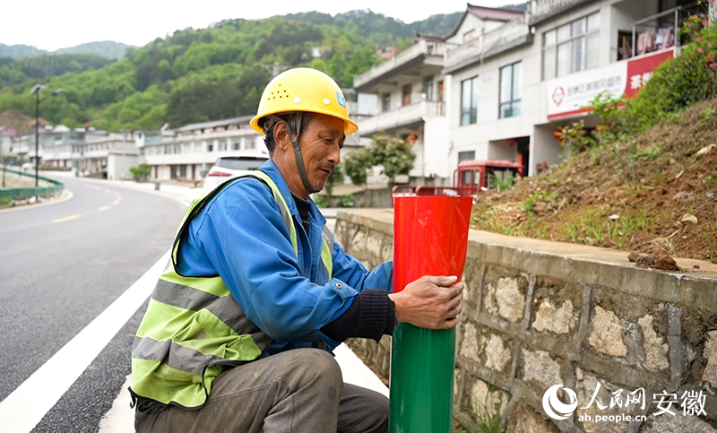 大灣村村民陶元佳正在路邊為護(hù)欄張貼反光貼。人民網(wǎng)記者 王銳攝