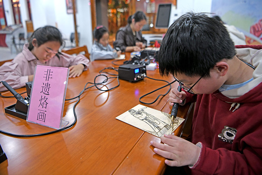 2024年5月5日，安徽省淮南市小朋友在淮南人民公園下沉廣場1952文化旅游街區(qū)體驗非遺烙畫。