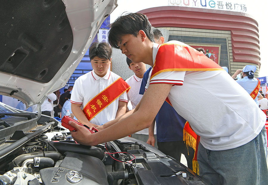安徽機械工業(yè)學(xué)校學(xué)生在淮南市2024年職業(yè)教育活動周現(xiàn)場展示汽車維修技能。