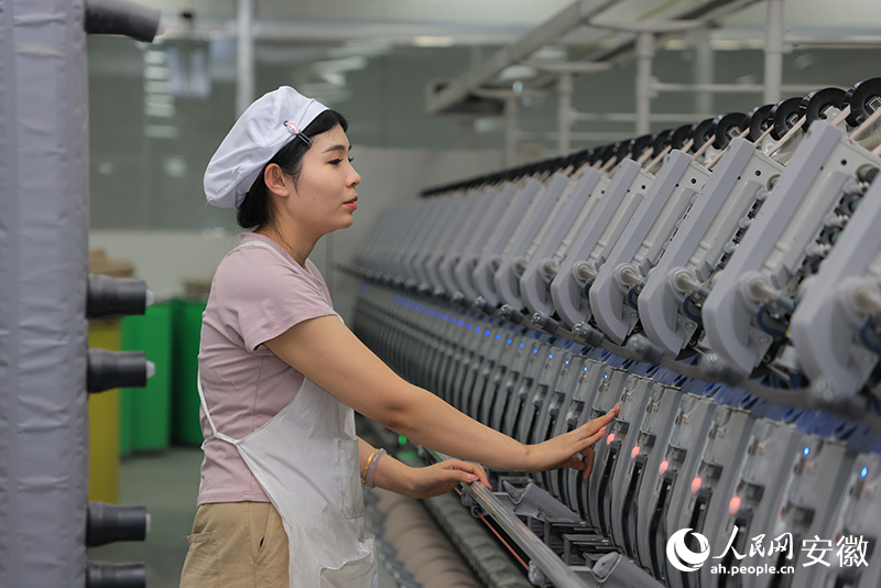 車間內(nèi)，一名女工正在操作紡織機(jī)器。人民網(wǎng)記者 王曉飛攝