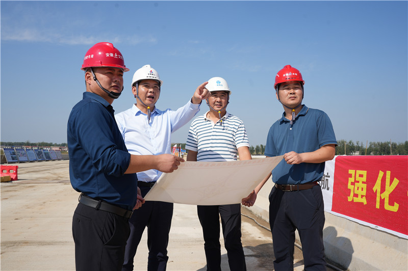 安徽建工集團宿州高速公路有限公司總經(jīng)理周忠（左二）正在和同事們確定現(xiàn)場施工狀況。人民網(wǎng)記者 王銳攝