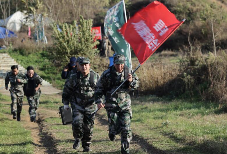 基層救援隊伍手握隊旗，攜帶物資裝備進行徒步行進科目。葛軍 攝
