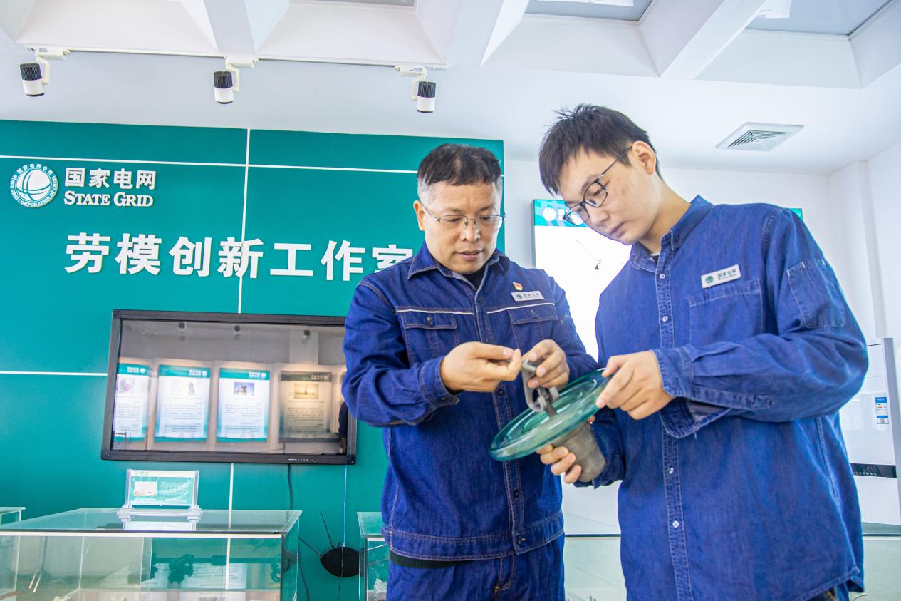 張濤（左）和徒弟在工作室里探討創(chuàng)新工器具的使用方法。王磊攝