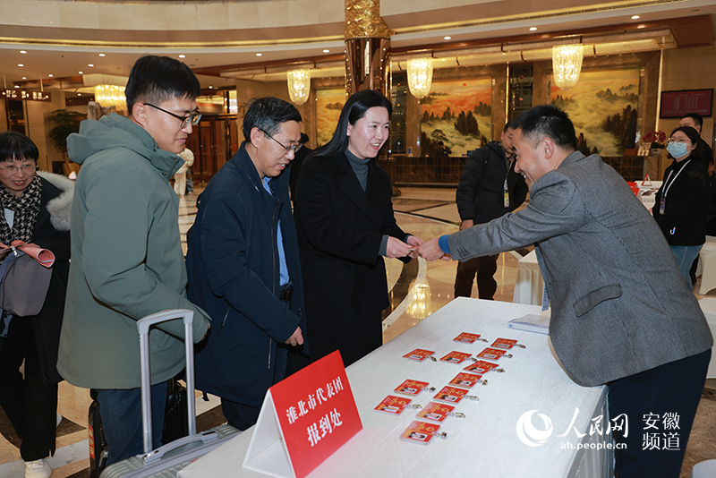 工作人員將證件遞給前來報(bào)到的代表。人民網(wǎng)記者 王曉飛攝