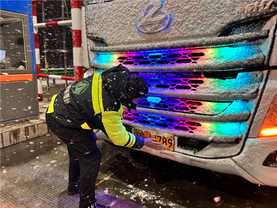 3月4日，蚌埠處固鎮(zhèn)東站仲虎為過(guò)往車輛清理車牌積雪。