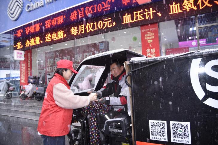安徽移動(dòng)志愿者把裝滿(mǎn)熱水的保溫杯遞送到快遞員手中。