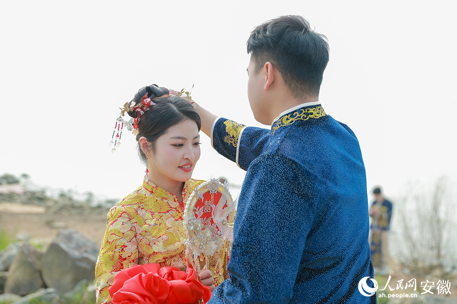 巢湖之畔，參加集體婚禮的新郎為新娘插上頭簪。人民網(wǎng)記者 張俊攝
