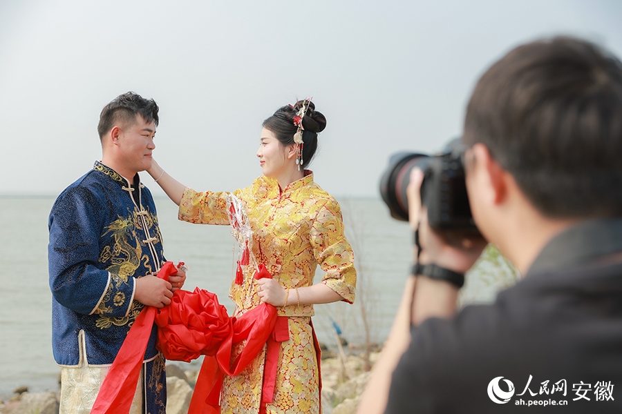 參加集體婚禮的新人在巢湖之畔拍照留影。人民網(wǎng)記者 張俊攝