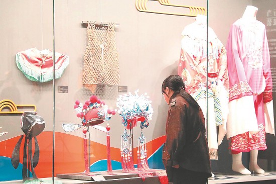 博物館內(nèi)，游客正在參觀戲服、盔帽等展品。