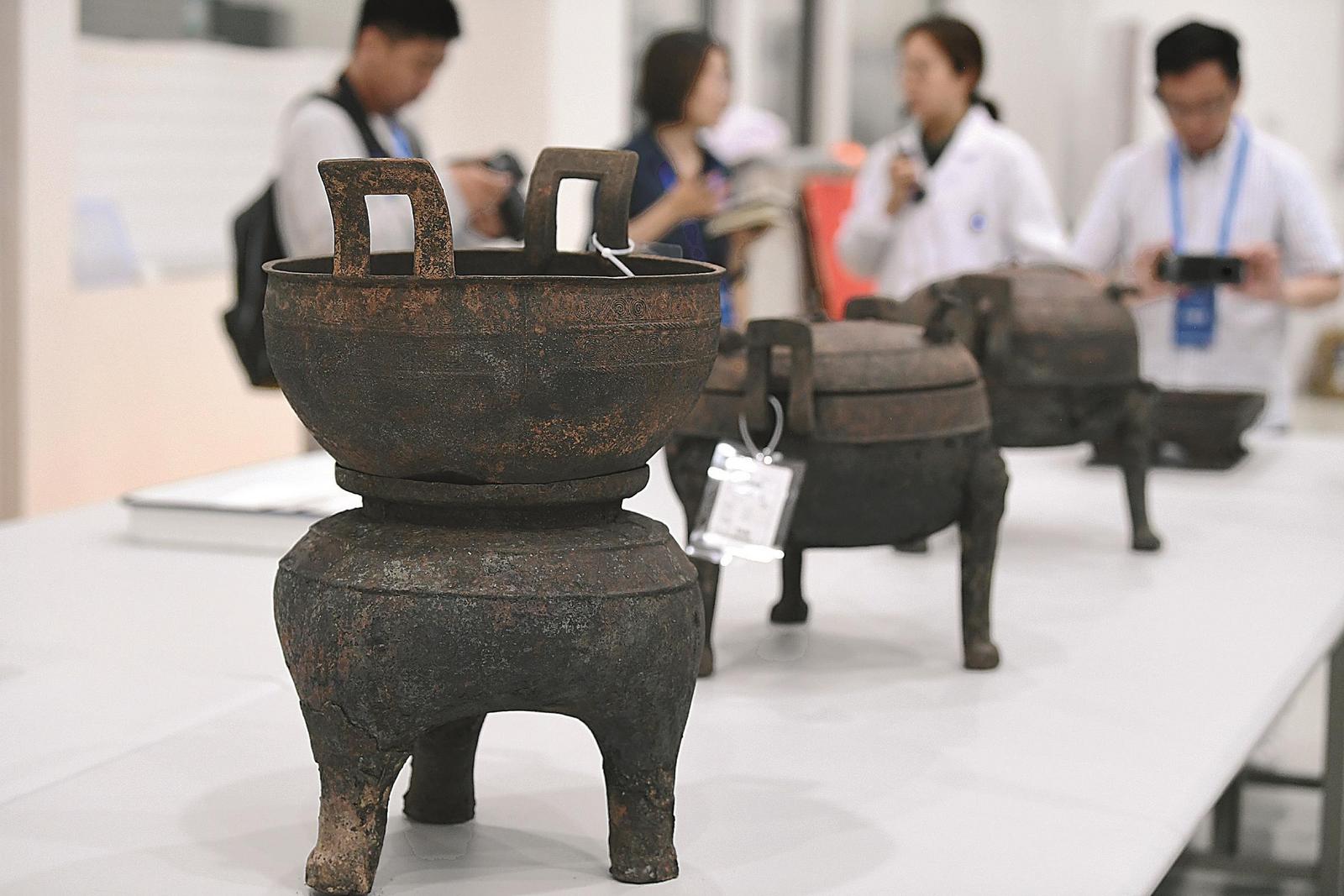 在淮南武王墩墓發(fā)掘現(xiàn)場(chǎng)，考古人員向記者介紹出土的青銅器。本報(bào)記者 徐旻昊 攝